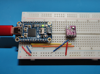 A picture of a breadboard with an FT232H adapter, a BME280 breakout board, and connecting wires.
