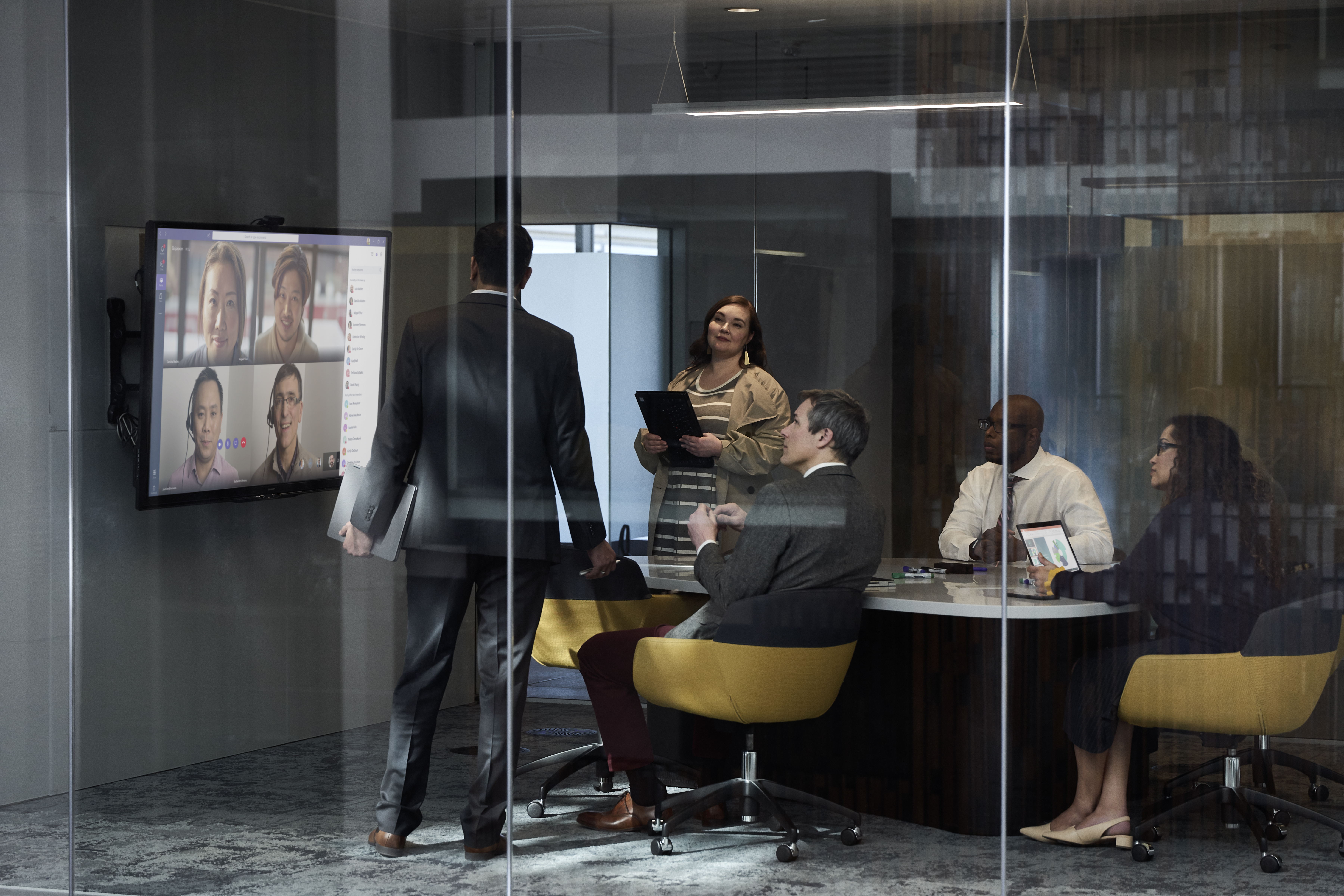 Un groupe d'employés de bureau lors d'une réunion discute d'images sur grand écran.