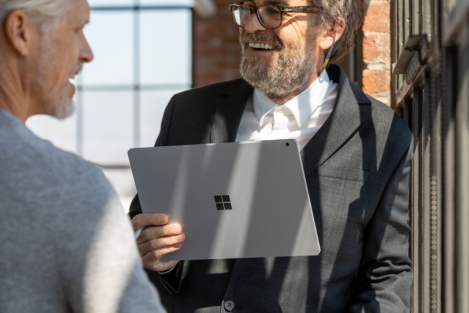 Microsoft Surface で会話をしている 2 人の写真。