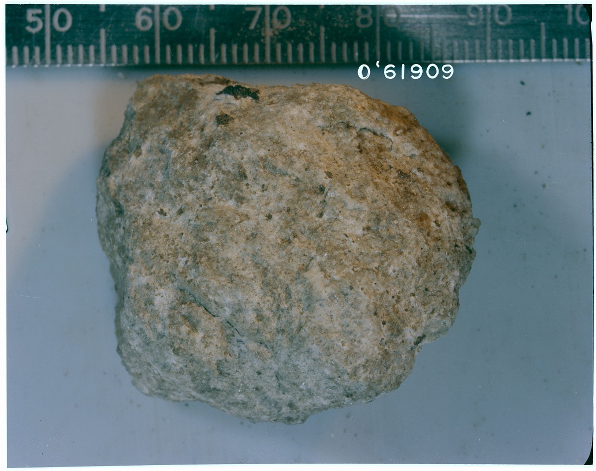 Photo of highland rock sitting next to a ruler on a flat surface.